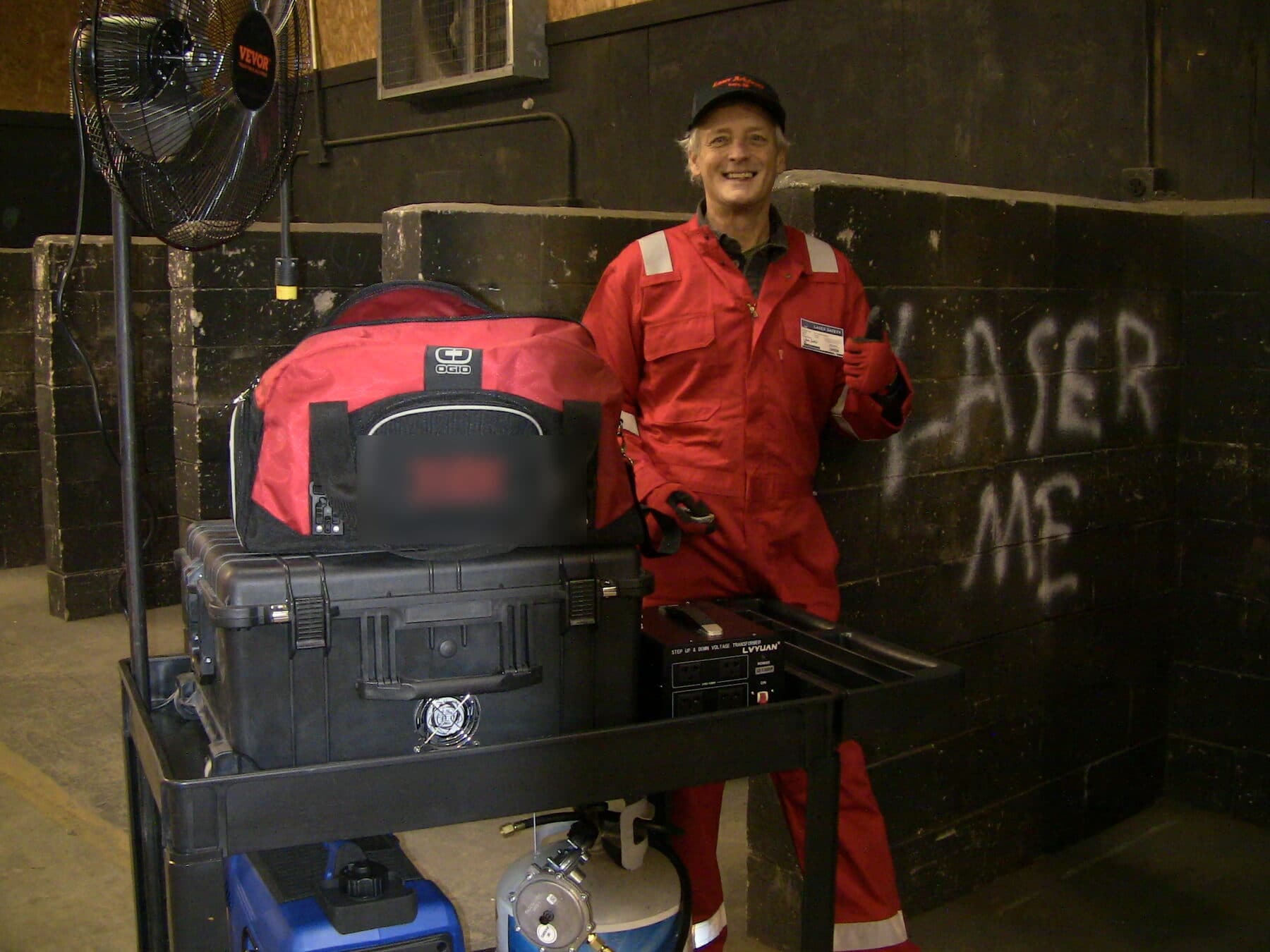 Jamie in laser safety gear beside the mobile rig — control case, transformer and generator